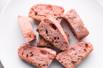 Overhead view of strawberry and chocolate sourdough on a white plate, top view of pink and chocolate artisan bread on a white background, open crumb artisan bread on white background