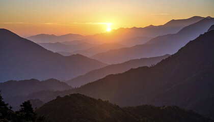 Obraz premium Breathtaking sunset over layered mountains, creating calm atmosphere with misty ridgelines