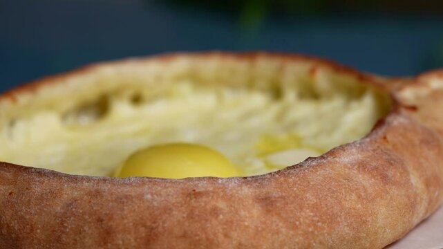 Golden crust khachapuri with smooth melted cheese and egg yolk centerpiece, delicious traditional dish.
