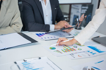 Business meeting using laptop computer, calculator, graph paper to analyze investment strategies and brainstorm financial ideas in office.