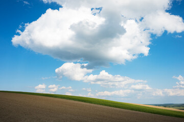 A clear blue sky with a few fluffy white clouds