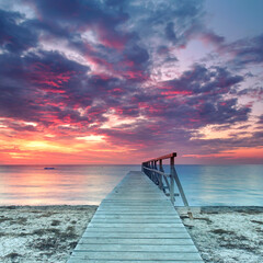 a Lonely weathered wooden pier Overlooking a Colorful Sunset by the Sea