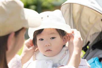 お母さんに帽子をかぶせてもらっている赤ちゃん
