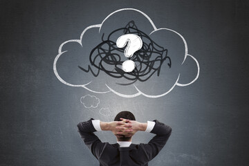 Businessman thinking with hands behind head facing chalk-drawn cloud and question mark symbolizing...