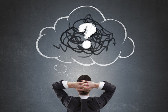 Businessman thinking with hands behind head facing chalk-drawn cloud and question mark symbolizing confusion and curiosity on dark background.