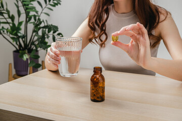 A woman holds omega-3 fish oil capsules. Healthy lifestyle, prevention and treatment of diseases. The woman takes and drinks dietary supplements and vitamins for skin, nails and hair. 