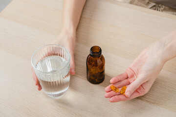 A woman holds omega-3 fish oil capsules. Healthy lifestyle, prevention and treatment of diseases. The woman takes and drinks dietary supplements and vitamins for skin, nails and hair. 
