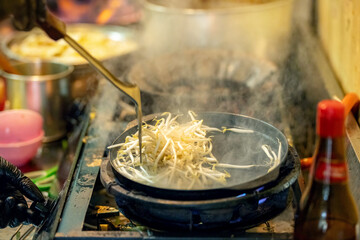 Pad Thai noodles is fried noodles cook in pan with big fire flame is hong kong style. Pad Thai famous Asian Thai street fast food in hot pan, Pad Thai is fried noodle dish a street food Thailand