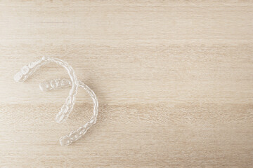 Transparent dental aligners placed on wooden surface with light background, showcasing orthodontic health and hygiene concept clearly. 3D Rendering