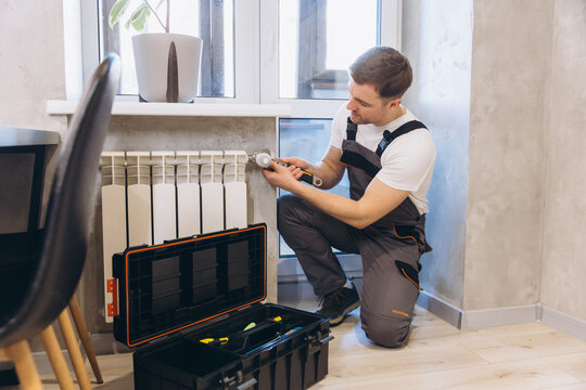 Professional plumber repairing heating system in modern apartment