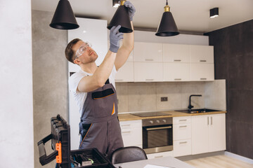 Electrician installing pendant lamp in modern kitchen