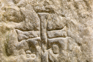 An engraved cross on a stone surface appears as an ancient symbol, carrying history and...