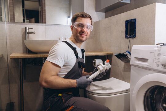 Professional plumber working on toilet fixture in modern bathroom - Powered by Adobe