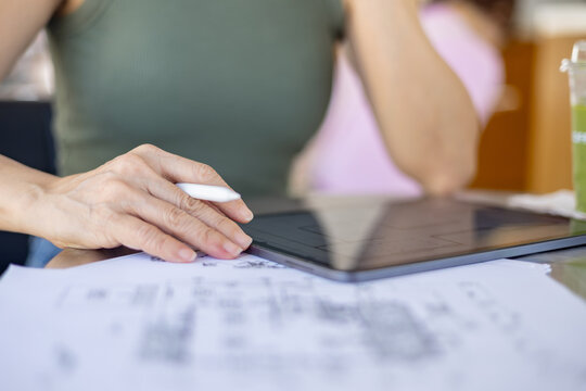 Female architect is using a tablet to design her work while sitting in a coffee shop