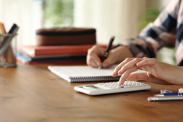 Student hand using scientific calculator and taking notes