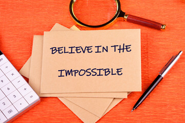 Motivational quote. BELIEVE IN THE IMPOSSIBLE text written on an envelope on a bright background,...