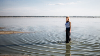 A young woman stands in the lake in water rings. Sad mood. Depressive state. Loneliness. Caucasian...