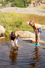 Two boys fishing with nets in a river on summer vacation