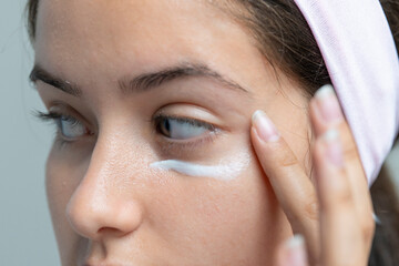 Woman applying under-eye cream for dark circles, a close-up on skincare beauty treatment.