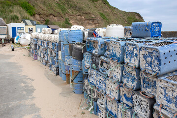Lobster and crab commercial fishing pots traps stacked  at a harbour port background backdrop. Made from recycled plastic containers.