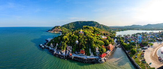 Wide panorama of a big seated golden Buddha statue on a lush green mountain at Hat Sai Noi in Khao...