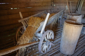 A wooden cart with hay on it is in a barn