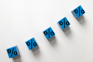 A rising line of percentage symbols on blue wooden cubes. Represents increasing interest rates, financial growth, inflation, investment returns,business profit growth,business and finance,math.