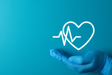 Doctor's or nurse's gloved hand holding a heart and heartbeat (EKG) line icon.,Concept for cardiology,cardiovascular health,medical care, heart check-up,health insurance,life insurance,cardiac care.