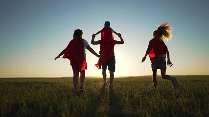 Happy family child play superheroes at sunset. child red capes run through open field embracing superhero fantasy. Family child bond during play at sunset. Superhero play strengthens family connection