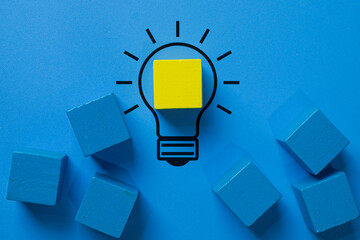 Creative solution,idea generation,innovation, brainstorming,problem-solving,breakthrough and creative thinking concept.,A yellow wooden block forms a glowing filament inside a lightbulb outline.