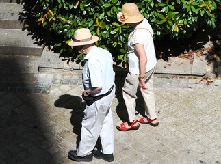 Verano con dos ancianos paseando por la calle con sombrero de paja