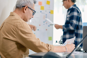 Obraz premium senior programmer bootcamlp,Asian young instructor guides senior learners through a programming on whiteboard, highlighting algorithm thinking and simple code exercises