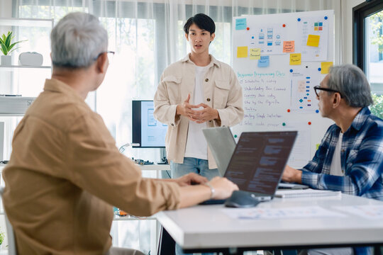 senior programmer bootcamlp,Asian young instructor guides senior learners through a programming on whiteboard, highlighting algorithm thinking and simple code exercises