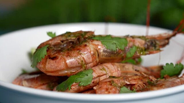 Stacked grilled shrimp in herb sauce, garnished with cilantro, served in a white bowl.
