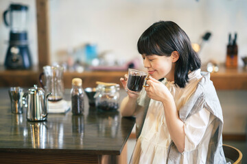落ち着いた雰囲気の空間で、コーヒーを淹れて飲む若い女性