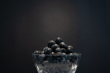 A bowl of blueberries against a black background. Food concept.