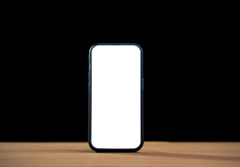 Smartphone with blank white screen mockup on wooden table against black background for technology and business concept.