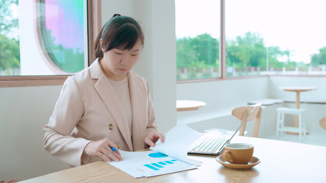  businesswoman analyzes a financial report with charts and data, planning a marketing strategy in a modern office.
