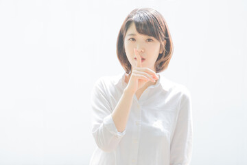 「秘密」のハンドサインをする若い女性