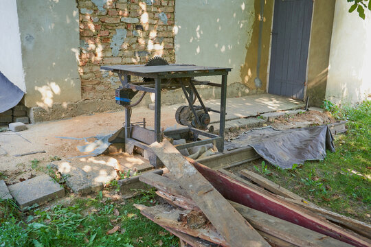 circular saw and old boards, in the village yard there is a circular saw with a table and old rotten boards, cutting boards for firewood
