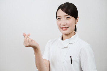 指でハートマークを作る白衣の女性
