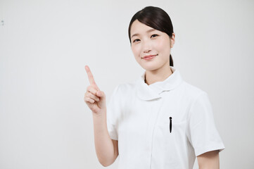 指さしのポーズをする白衣の女性