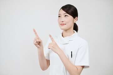 指さしのポーズをする白衣の女性