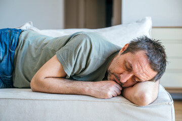 Desperate sad man laying on sofa couch, feeling miserable and depressed