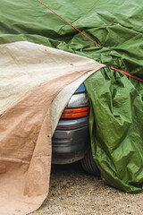 Car cover, vehicle parked by the old building with protective covering