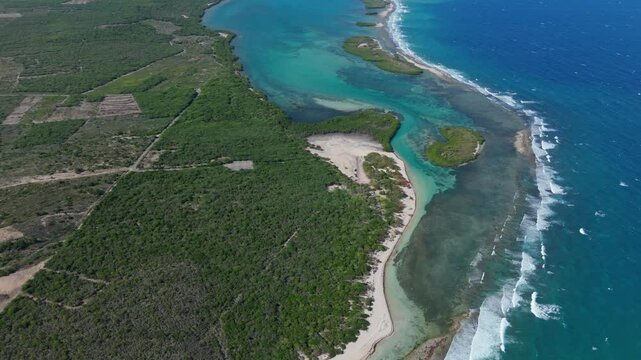 Aerial top down of blue turquoise lagoon of Playa Caobita, Azua. green islands with Caribbean sea waves.