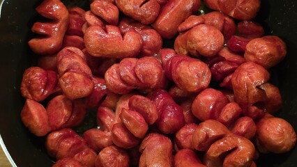Fried cocktail sausages in pan close-up
