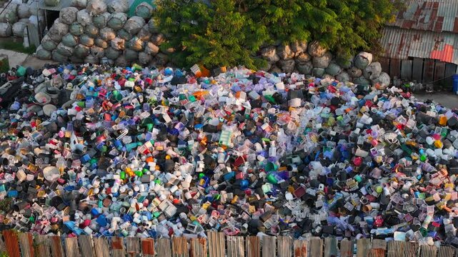 Aerial close up view of pile of discarded plastic containers and household items in an fenced dump