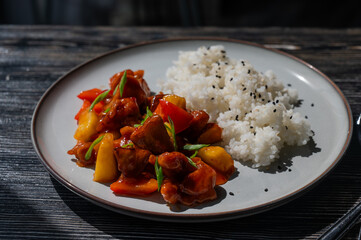 Pork in sweet and sour sauce with boiled rice on a plate. 