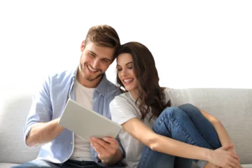 Selbstklebende Fototapeten Young couple watching media content online in a tablet sitting on a sofa on a transparent background © ty